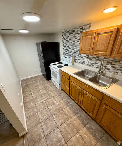 3918 Mapleleaf Way West Jordan, UT 84088 - Photo 2 of 12 Kitchen featuring electric stove, decorative backsplash, light countertops, wood finish cabinets, and light tile patterned floors