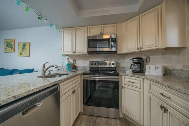 a kitchen with granite countertop white cabinets stainless steel appliances and a sink