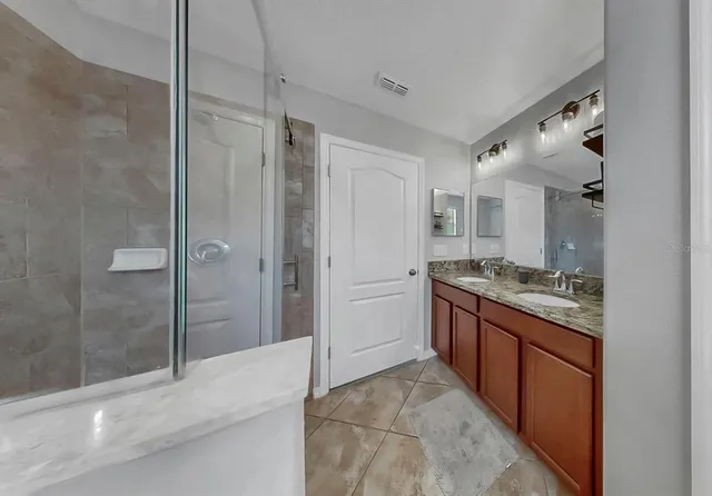 a kitchen with stainless steel appliances granite countertop a stove top oven a sink dishwasher a refrigerator and white cabinets with wooden floor