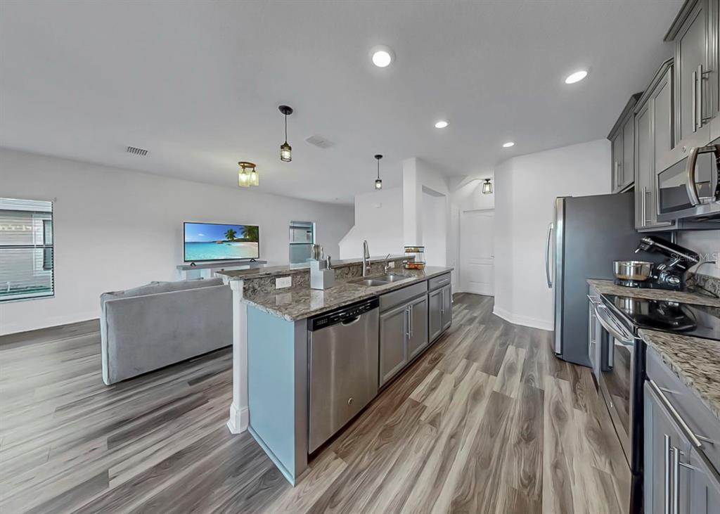 10136 Newminster Loop Ruskin, FL 33573 - Photo 37 of 64 a kitchen with stainless steel appliances granite countertop a stove top oven a sink dishwasher a refrigerator and white cabinets with wooden floor