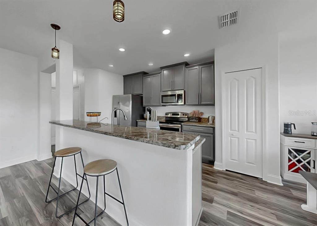 10136 Newminster Loop Ruskin, FL 33573 - Photo 39 of 64 a kitchen with kitchen island granite countertop stainless steel appliances cabinets a sink and a counter top space