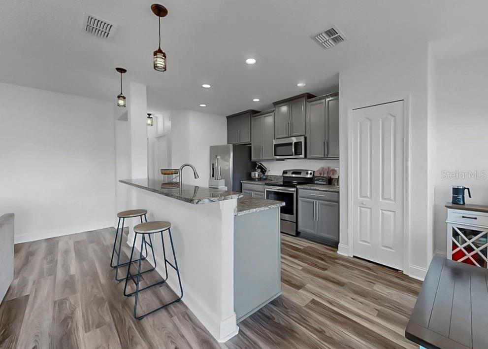 10136 Newminster Loop Ruskin, FL 33573 - Photo 42 of 64 a kitchen with granite countertop a refrigerator stove and wooden floor