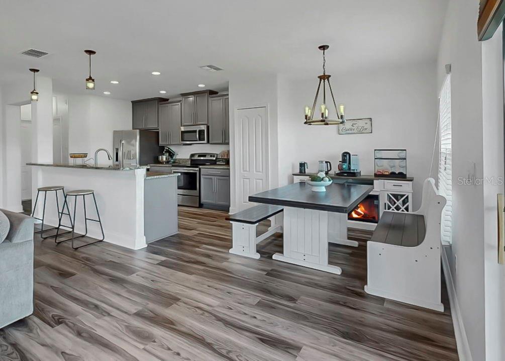 10136 Newminster Loop Ruskin, FL 33573 - Photo 6 of 64 a kitchen with a sink dishwasher a stove and white cabinets with wooden floor