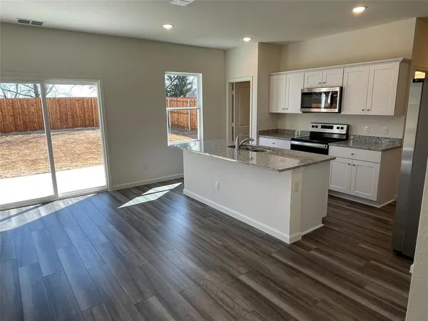 a kitchen with stainless steel appliances granite countertop a stove a sink and a microwave