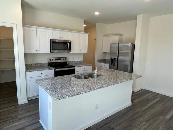 a kitchen with kitchen island granite countertop a sink stove and refrigerator