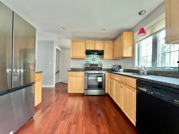 a kitchen with stainless steel appliances a refrigerator sink and wooden floor