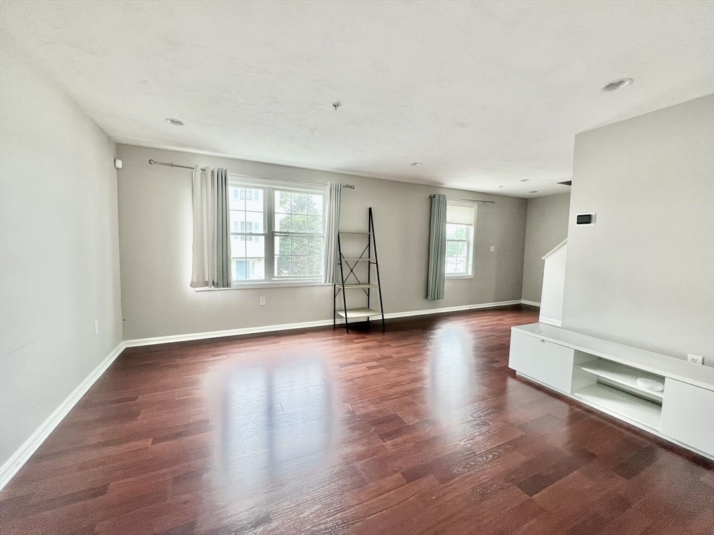 1005 Trapelo Road, Unit 3 Waltham, MA 02452 - Photo 4 of 19 a view of an empty room with wooden floor and a window
