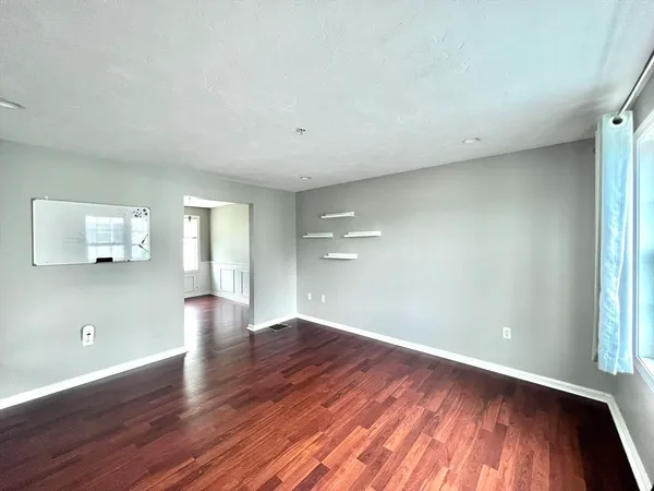 a view of an empty room with wooden floor and a window