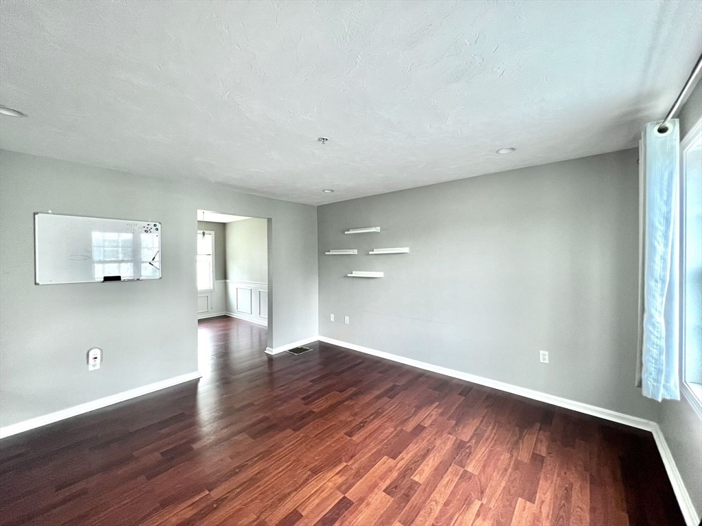 1005 Trapelo Road, Unit 3 Waltham, MA 02452 - Photo 5 of 19 a view of an empty room with wooden floor and a window