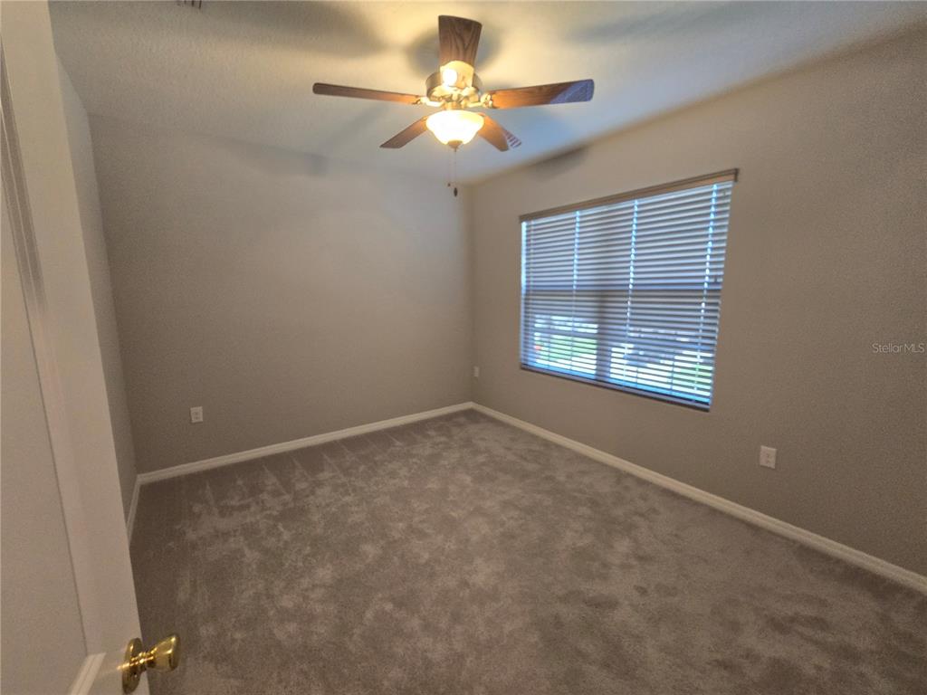 5846 Southwest 80th Lane Ocala, FL 34476 - Photo 23 of 27 an empty room with a chandelier fan and windows