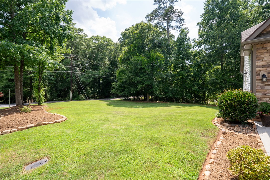 201 Hearthstone Drive Anderson, SC 29621 - Photo 5 of 49 A verdant, open lawn borders a natural woodland, offering serene outdoor space.