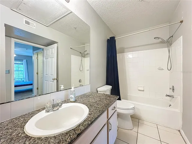 a bathroom with a granite countertop toilet sink and mirror