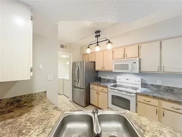 a kitchen with granite countertop a sink a counter top space appliances and cabinets