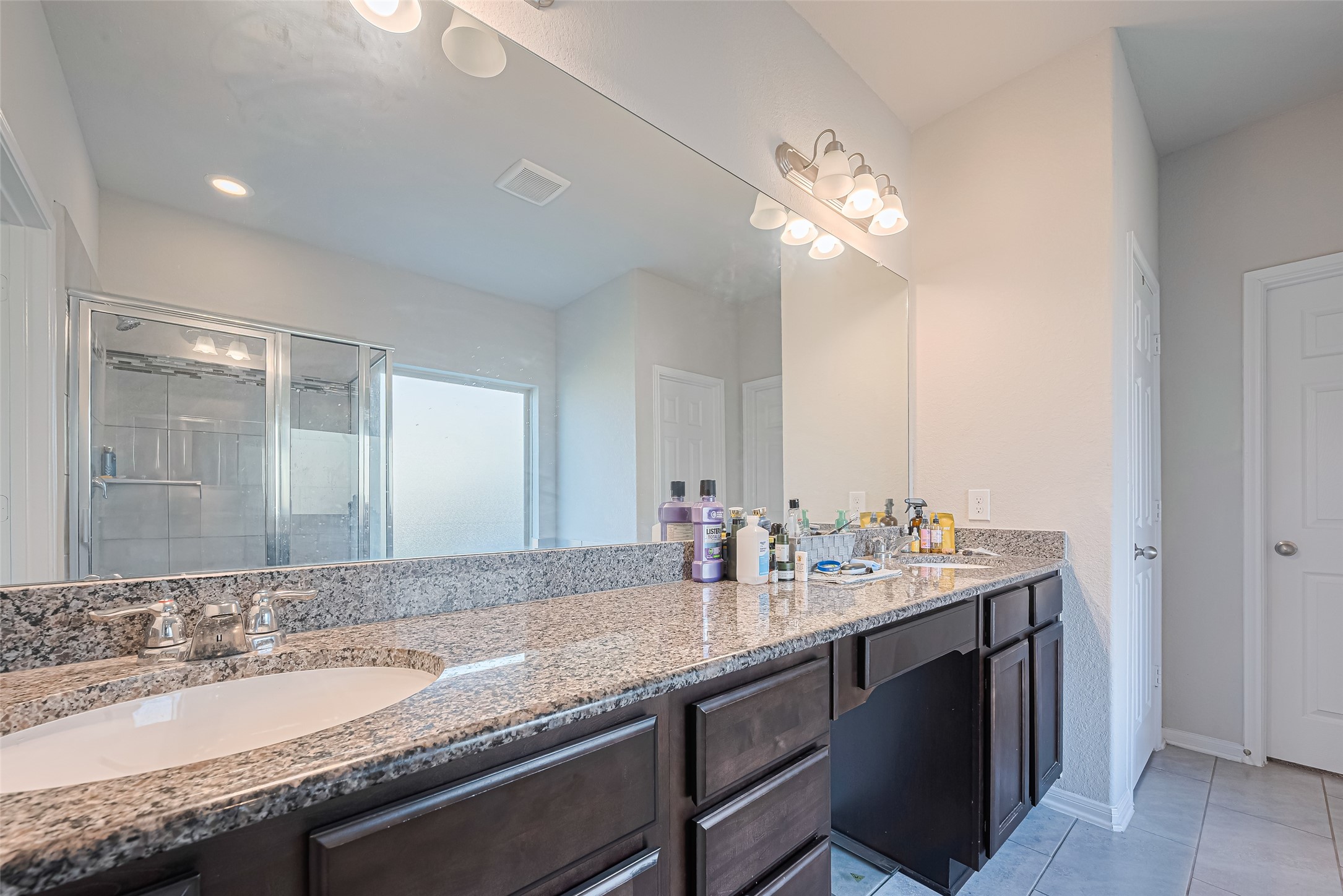 4507 Shallow Hill Court Houston, TX 77084 - Photo 36 of 50 a bathroom with a granite countertop sink a large mirror and a light fixture