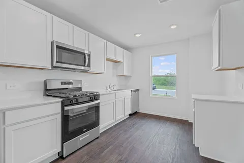 a kitchen with stainless steel appliances white cabinets and a wooden floor