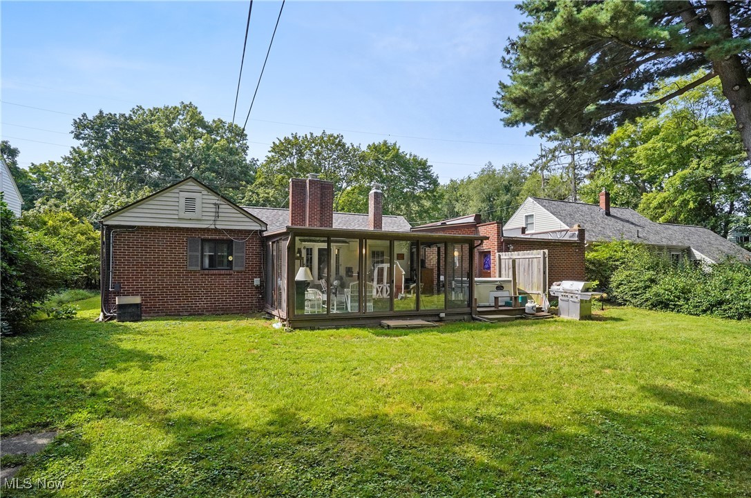 2829 Lee Road Silver Lake, OH 44224 - Photo 24 of 30 Rear view of house with a lawn, a sunroom, and central AC