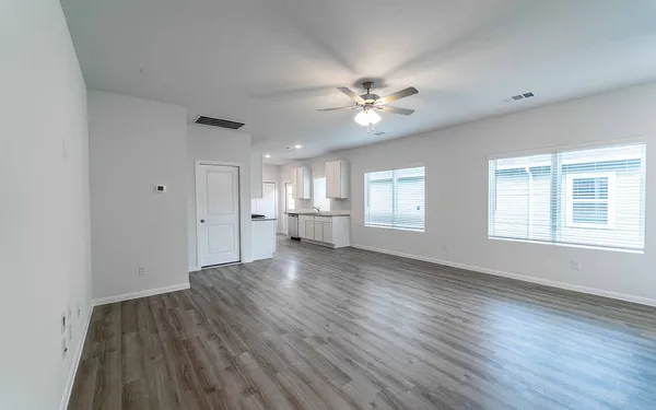 a view of an empty room with a window and wooden floor