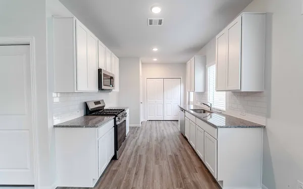 a kitchen with granite countertop sink stainless steel appliances and cabinets