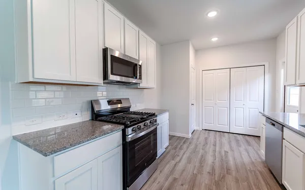 a kitchen with stainless steel appliances granite countertop a stove a sink and a microwave