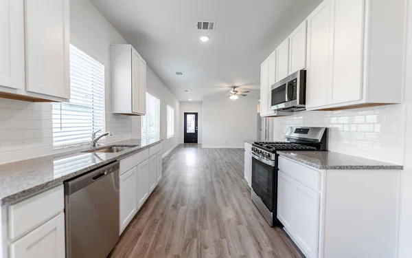 a kitchen with stainless steel appliances granite countertop a sink a stove top oven a counter space and cabinets