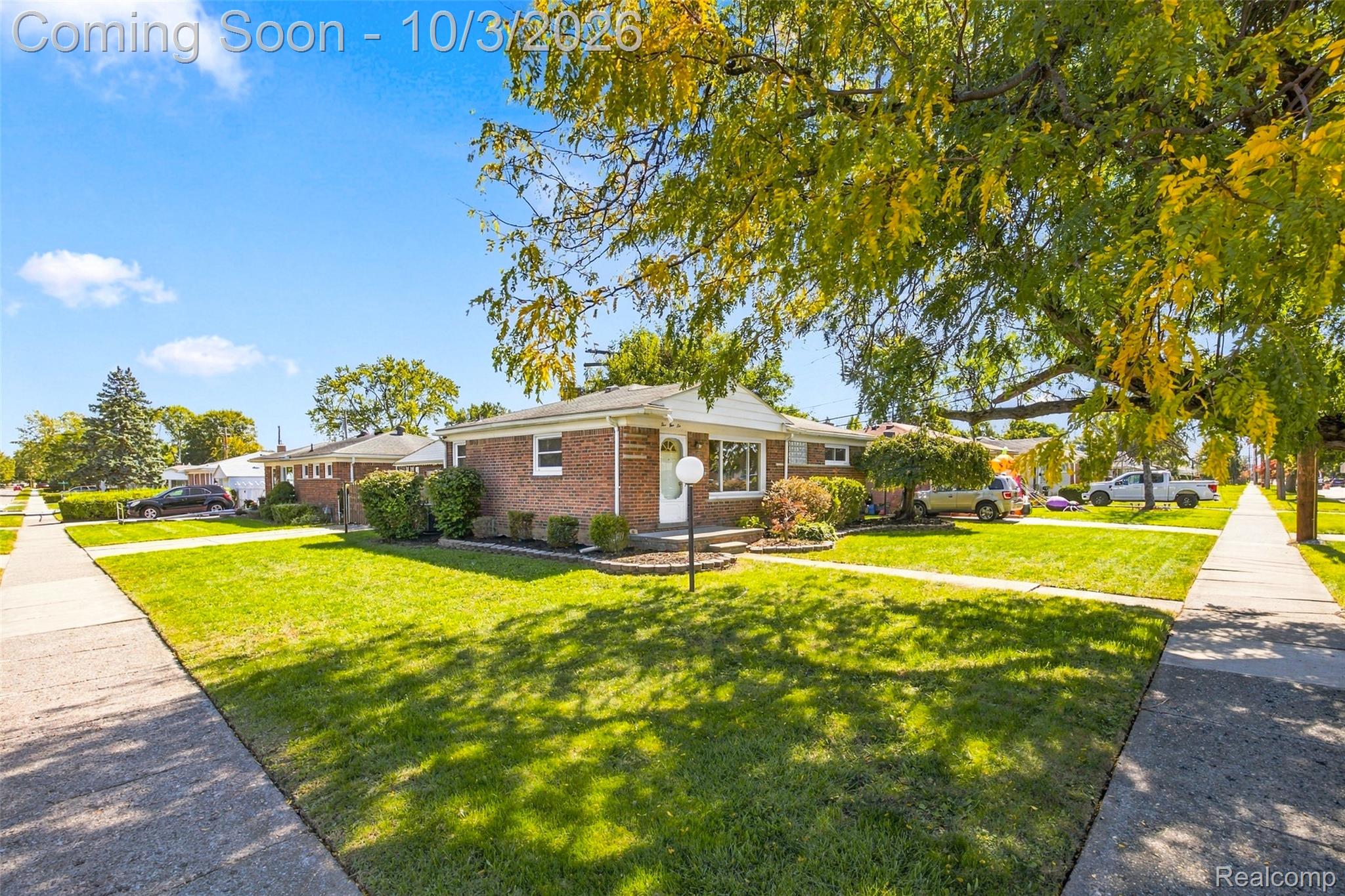 556 Henry Ruff Road Garden City, MI 48135 - Photo 37 of 49 Brick exterior with white trim, a manicured front lawn, established landscaping, and mature trees providing natural shade