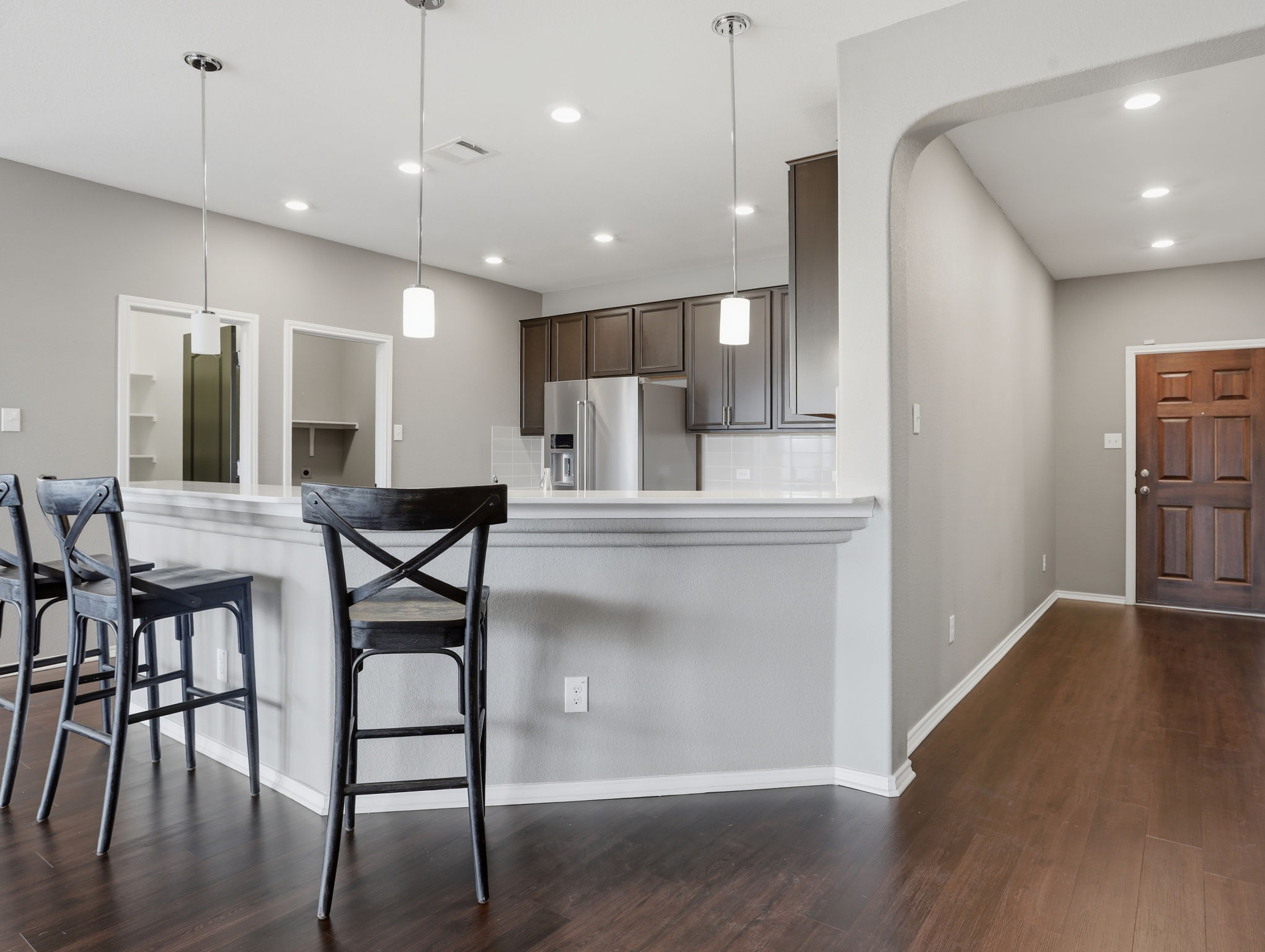 640 Landon Samuel Loop Pflugerville, TX 78660 - Photo 14 of 33 Kitchen featuring dark wood-finish cabinetry, stainless steel refrigerator, white subway tile backsplash, and a breakfast bar with pendant lighting