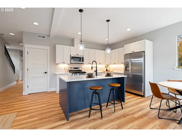 a kitchen with stainless steel appliances kitchen island granite countertop a refrigerator a stove a sink dishwasher and a wooden cabinets with wooden floor
