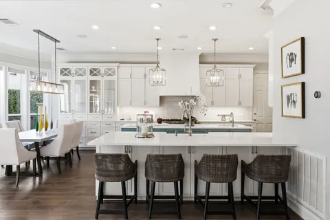 a kitchen with granite countertop a dining table chairs and white cabinets