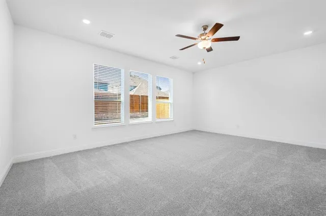 an empty room with ceiling fan and window