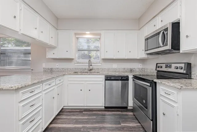 a kitchen with granite countertop cabinets stainless steel appliances and a sink