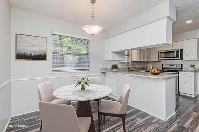 a kitchen with stainless steel appliances a dining table chairs and a refrigerator