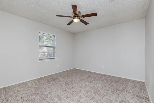 an empty room with a window and a ceiling fan