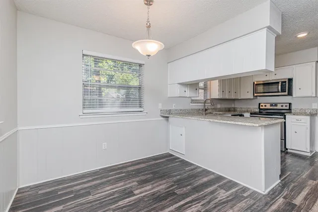 a kitchen with granite countertop a stove a sink and a microwave