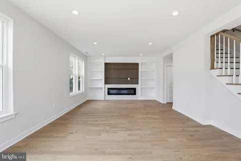 a view of an empty room with a window and a kitchen