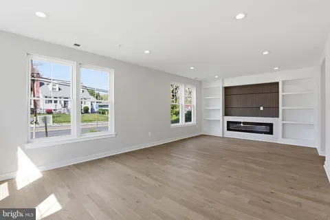 a view of an empty room with a window and a kitchen