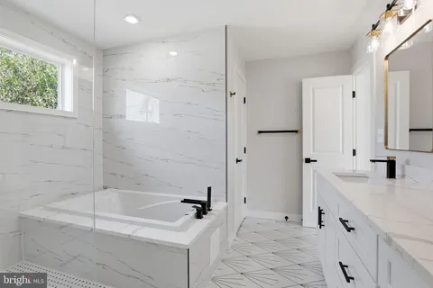 a bathroom with a tub sink and mirror