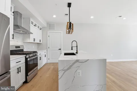 a kitchen with stainless steel appliances granite countertop a sink a stove and a refrigerator