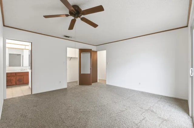an empty room with ceiling fan and window
