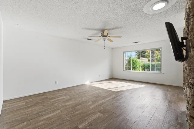 an empty room with wooden floor and windows