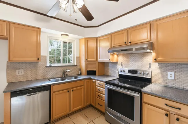 a kitchen with stainless steel appliances granite countertop a sink a stove and a counter space