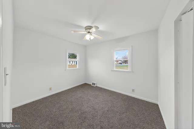 an empty room with a window and a fan