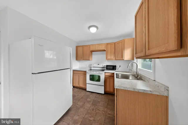 a kitchen with stainless steel appliances granite countertop a refrigerator a stove a sink and a white cabinets