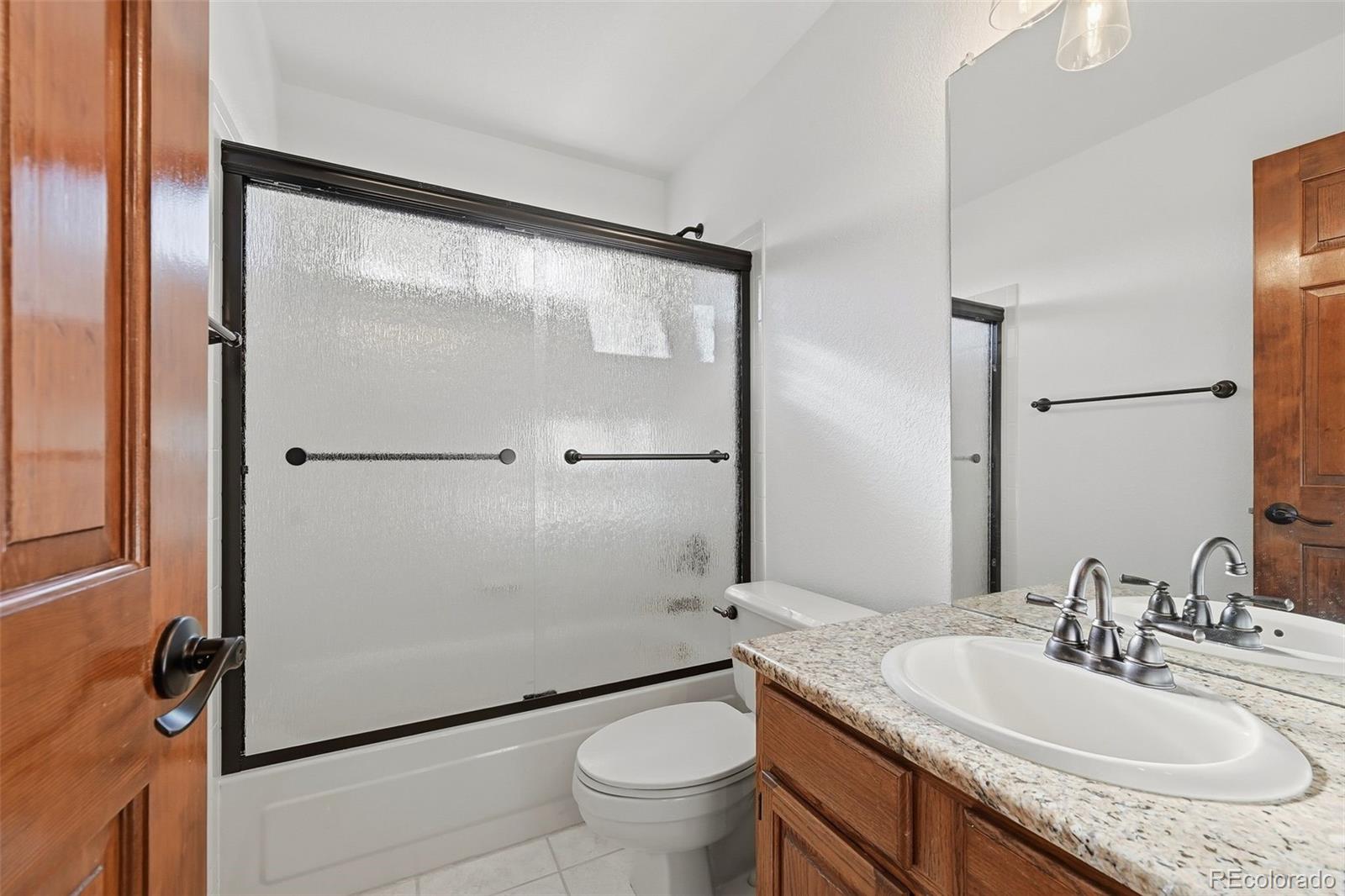 9372 Prairie View Drive Highlands Ranch, CO 80126 - Photo 33 of 50 a bathroom with a granite countertop sink toilet a mirror and shower