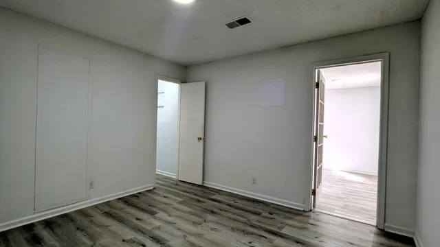 an empty room with wooden floor and windows