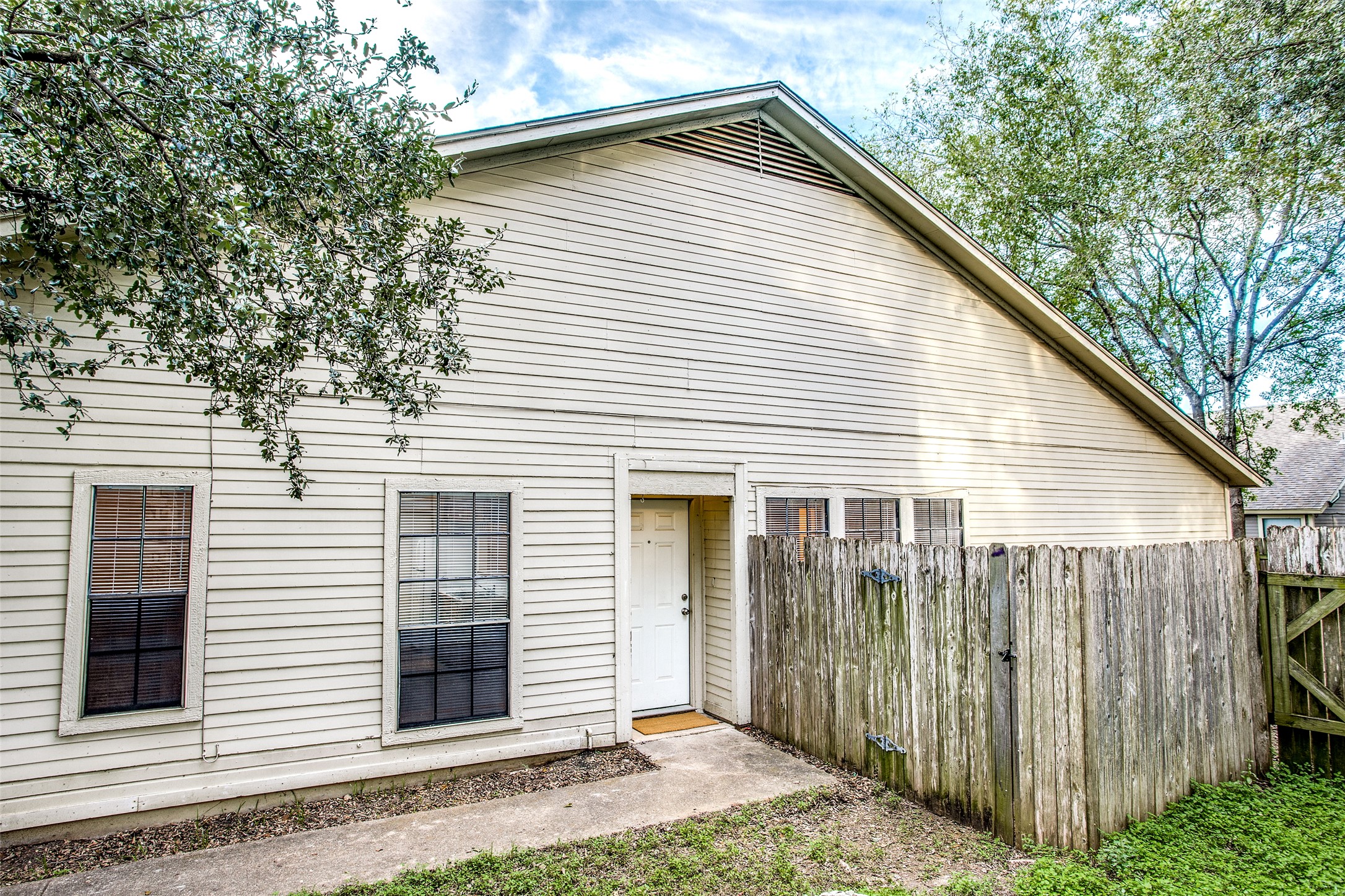 8811 Clearbrook Trail Austin, TX 78729 - Photo 3 of 38 rt B - A cream-colored siding residence features a charming entryway and a weathered wooden fence, enhancing its curb appeal.