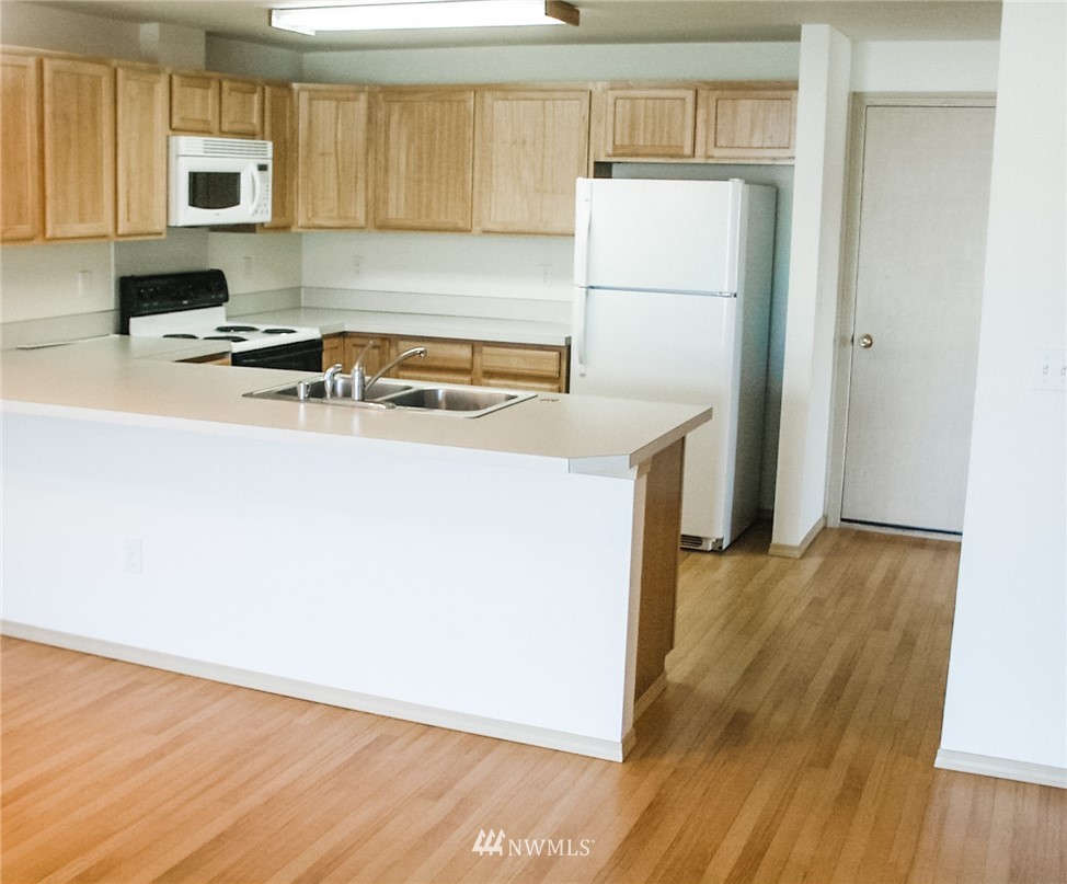 19723 Isabella Lane Southwest Rochester, WA 98579 - Photo 2 of 11 a white refrigerator freezer sitting inside of a kitchen with stainless steel appliances wooden floor and cabinets