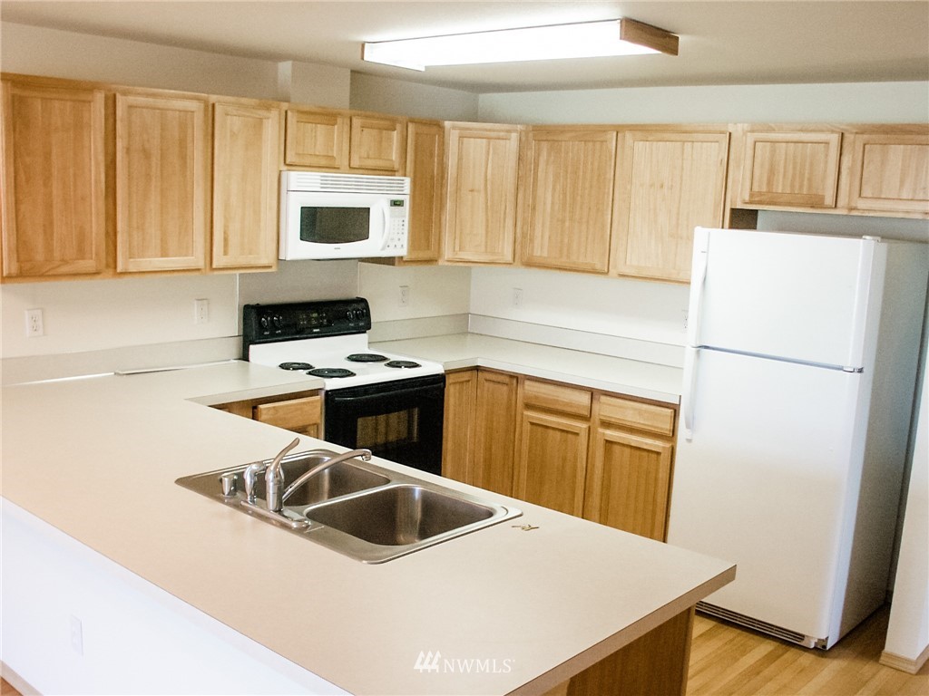 19723 Isabella Lane Southwest Rochester, WA 98579 - Photo 3 of 11 a kitchen with granite countertop a refrigerator a stove top oven a sink and dishwasher with wooden floor