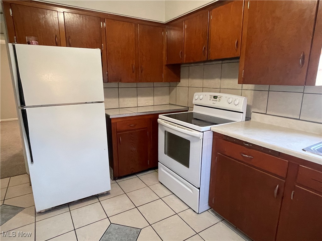 19860 Lorain Road, Unit 1 Cleveland, OH 44126 - Photo 5 of 8 Kitchen featuring decorative backsplash, white appliances, light tile patterned floors, and light countertops