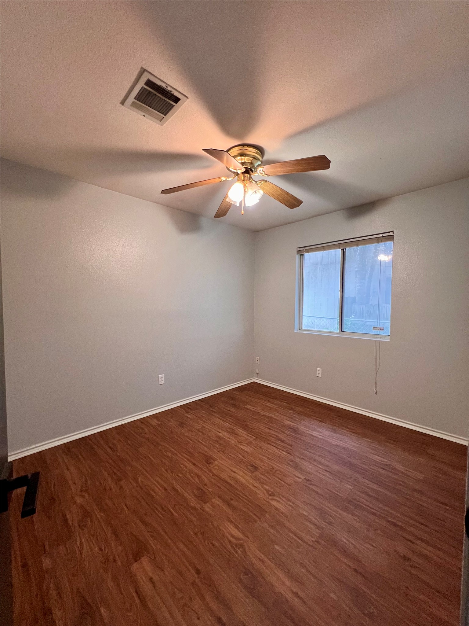 5404 China Berry Road Austin, TX 78744 - Photo 14 of 20 Well-lit room with wood flooring and a ceiling fan, offering a comfortable living space.