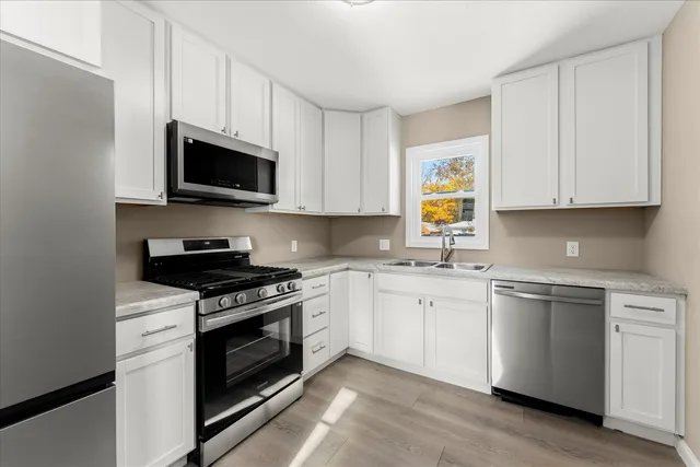 a kitchen with stainless steel appliances granite countertop grey cabinets a sink and a stove